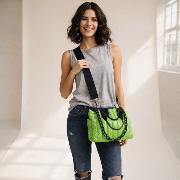 Woman holding a green quilted nylon tote with a black strap against a neutral background
