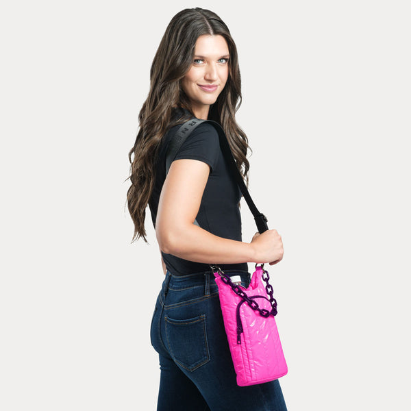 Woman holding a pink water bottle bag with a black strap against a light gray background