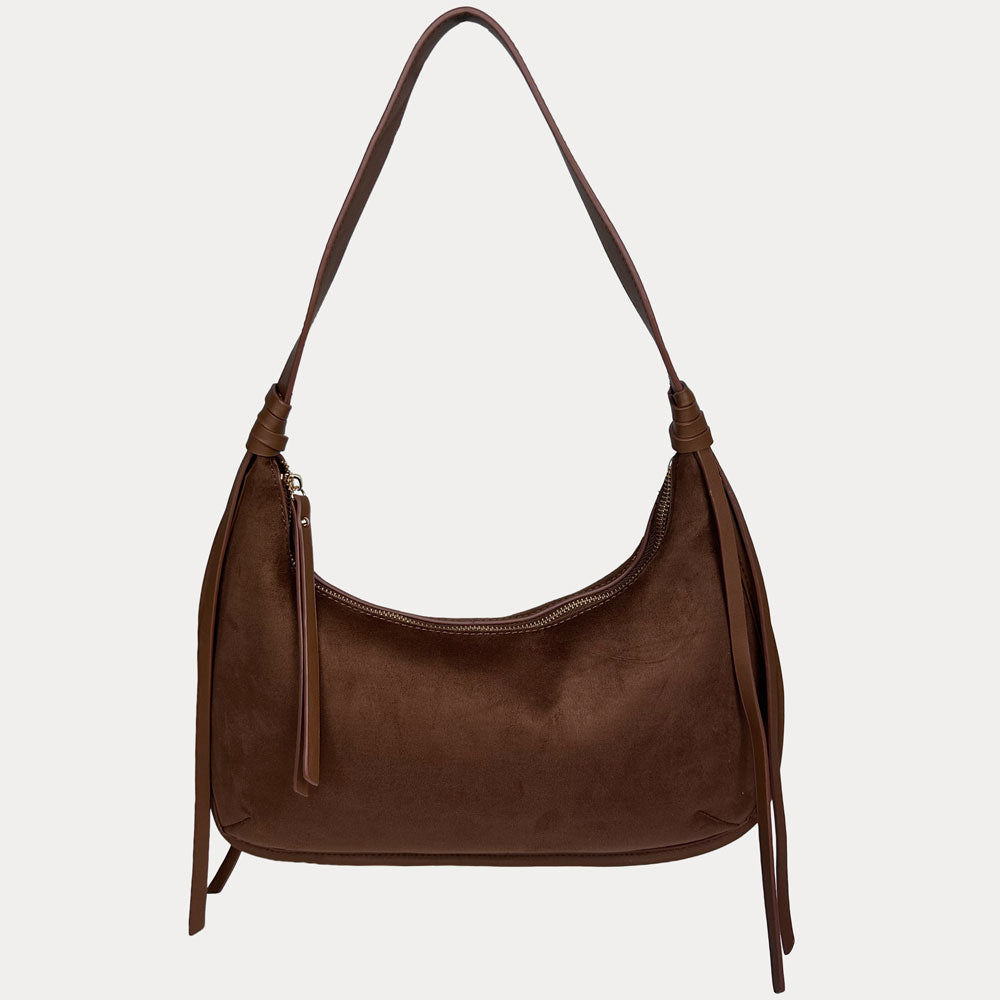 A chocolate vegan suede shoulder bag with a vegan leather details, shown against a light gray 