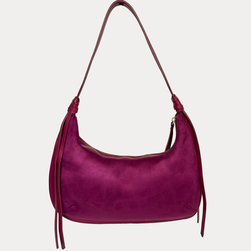 A burgundy vegan suede shoulder bag with vegan leather strap and hanging tassels, shown against a light gray background.