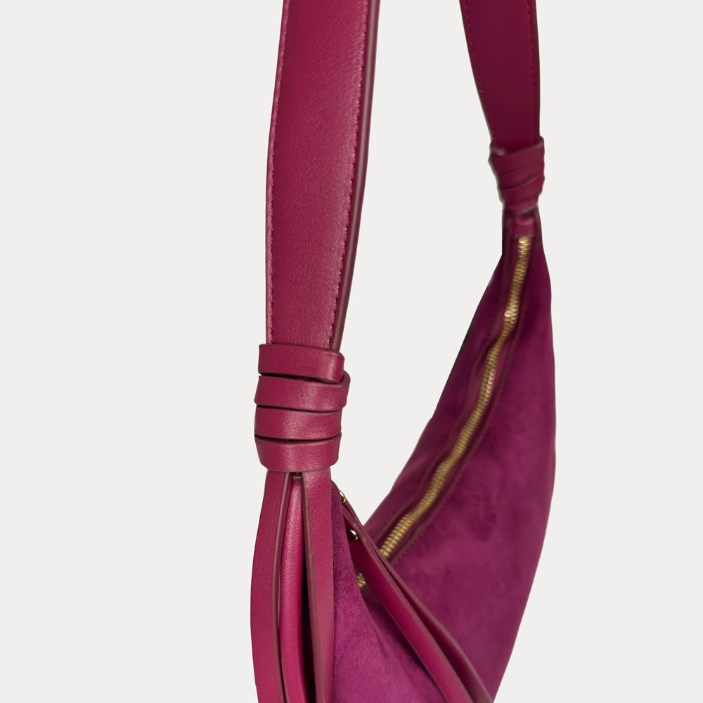 A close-up of a burgundy leather shoulder bag strap, set against a light gray background.