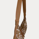 Close-up of a shoulder bag with  camel vegan leather strap and deer print body, shown against a light gray background.