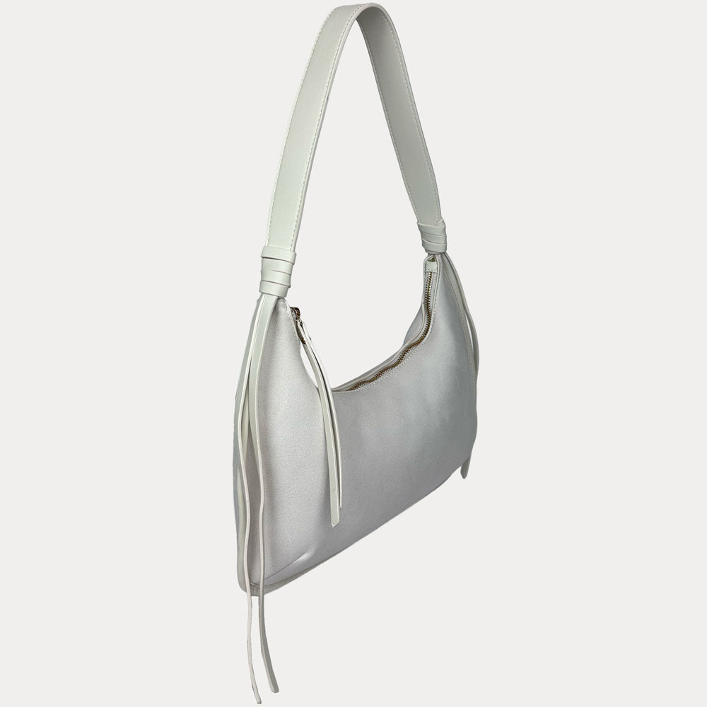 A cream vegan suede shoulder bag with a vegan leather strap and tassel details, shown from a side profile view against a light gray background.