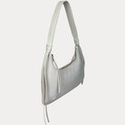 A cream vegan suede shoulder bag with a vegan leather strap and tassel details, shown from a side profile view against a light gray background.