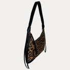 A shoulder bag with a brown and black leopard print body and solid black strap, shown against a light gray background.