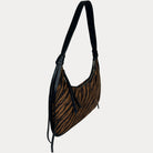 A shoulder bag with a brown and black tiger stripe pattern, featuring black vegan leather trim, shown against a light gray background.