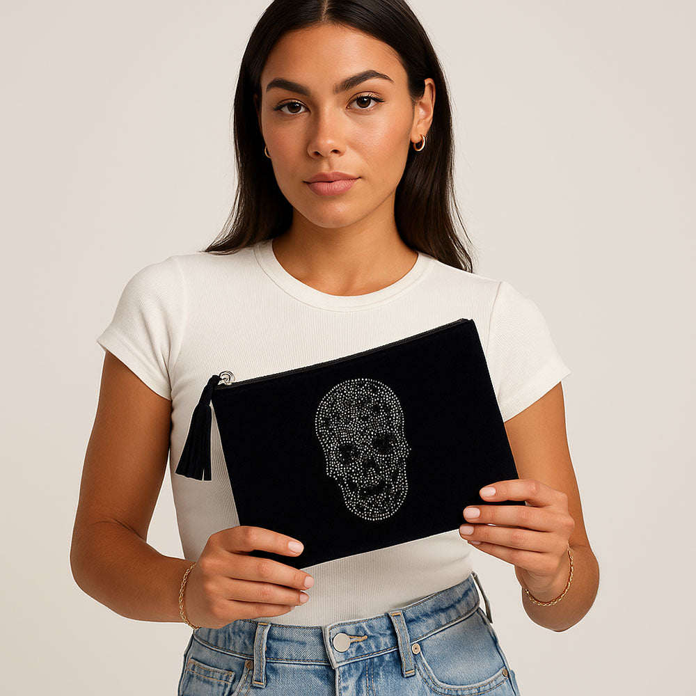 Woman holding a black pouch with a skull design on a plain background