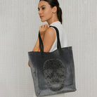 Woman holding a Grey Tote over her shoulder.  Neutral Background