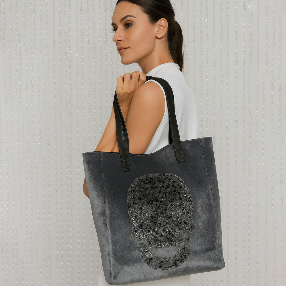 Woman holding the Sophie Grey Tote with rhinestone skull over her shoulder.  Neutral Background