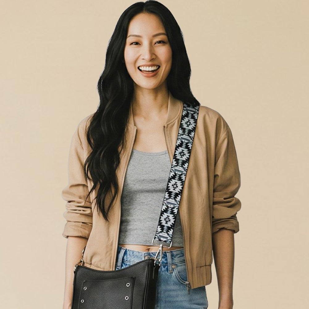 Woman wearing a beige jacket with a black handbag and patterned strap on a beige background